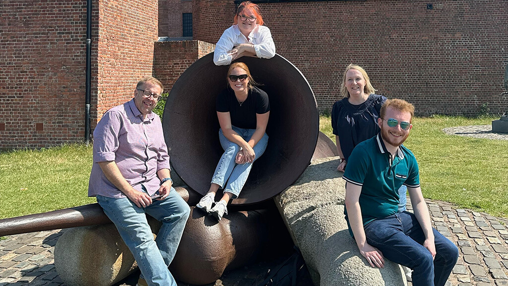 A group of people enjoying a fun treasure hunt game near a large, unique sculpture in Liverpool.
