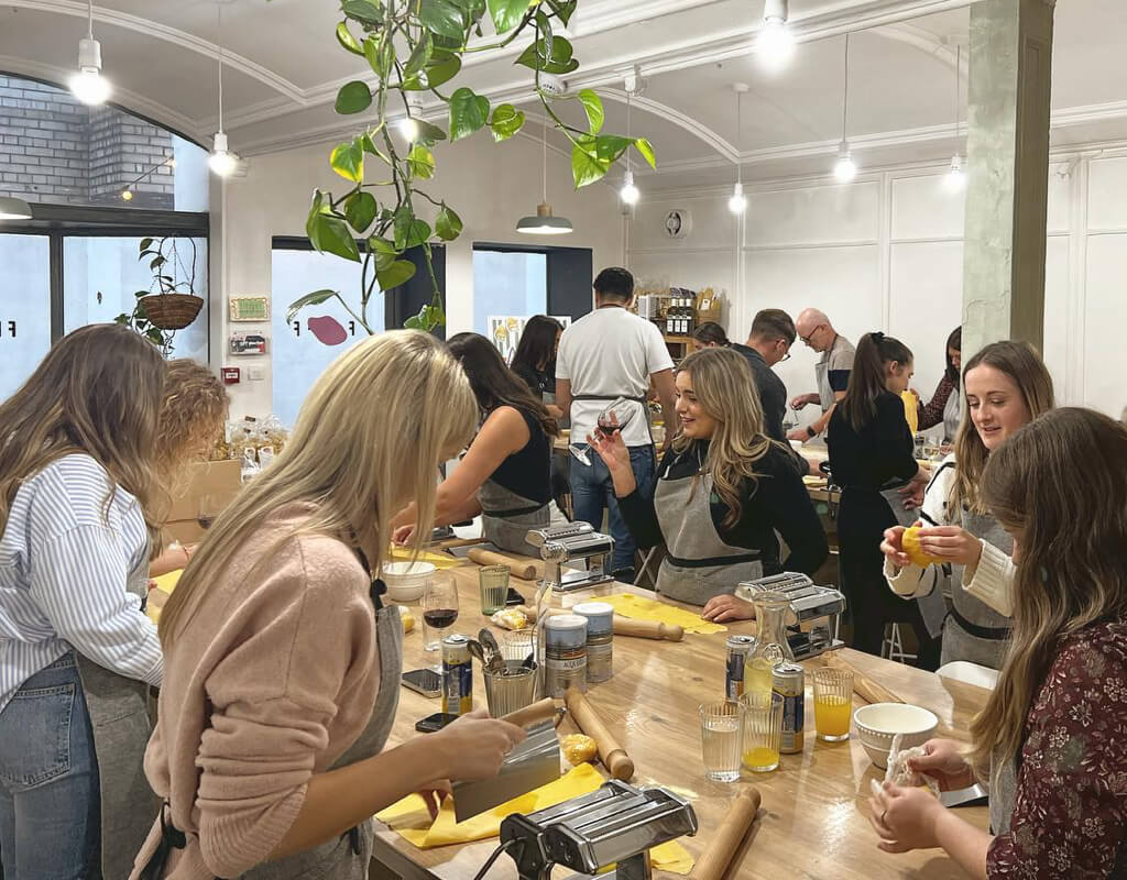 Group of friends at a cookery masterclass, a unique activity for a Liverpool hen do weekend.