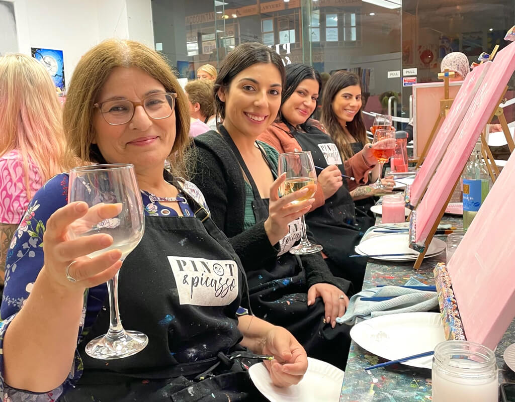 Group of hens enjoying a painting session at Pinot and Picasso, a creative hen do idea in Liverpool.